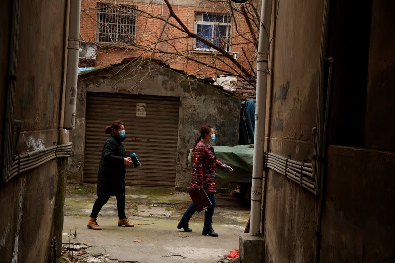 Members of a neighbourhood committee carry a loudspeaker playing a public safety announcement in Jiujiang