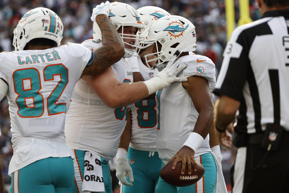 Miami Dolphins quarterback Tua Tagovailoa, right, is congratulated by teammates after his touchdown during the first half of an NFL football game against the New England Patriots, Sunday, Sept. 12, 2021, in Foxborough, Mass. (AP Photo/Winslow Townson)