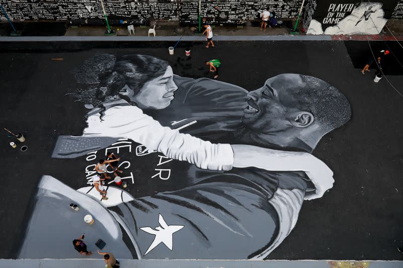Fans polish the mural in memory of Kobe Bryant and his daughter Gianna