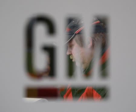 A worker walks behind a logo of General Motors after the announcement of the closing of the Opel assembly plant in Antwerp January 21, 2010. REUTERS/Francois Lenoir