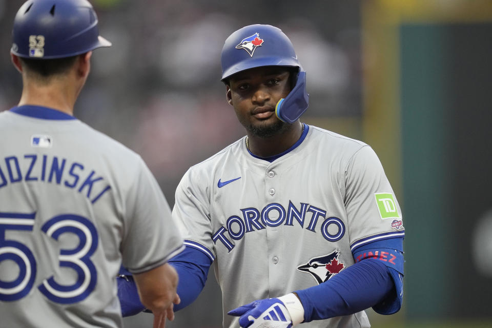 Toronto Blue Jays' Orelvis Martinez, right, is congratulated at first base by first base coach Mark Budzinski following his first hit in the majors, during the sixth inning of the team's baseball game against the Cleveland Guardians, Friday, June 21, 2024, in Cleveland. (AP Photo/Sue Ogrocki)