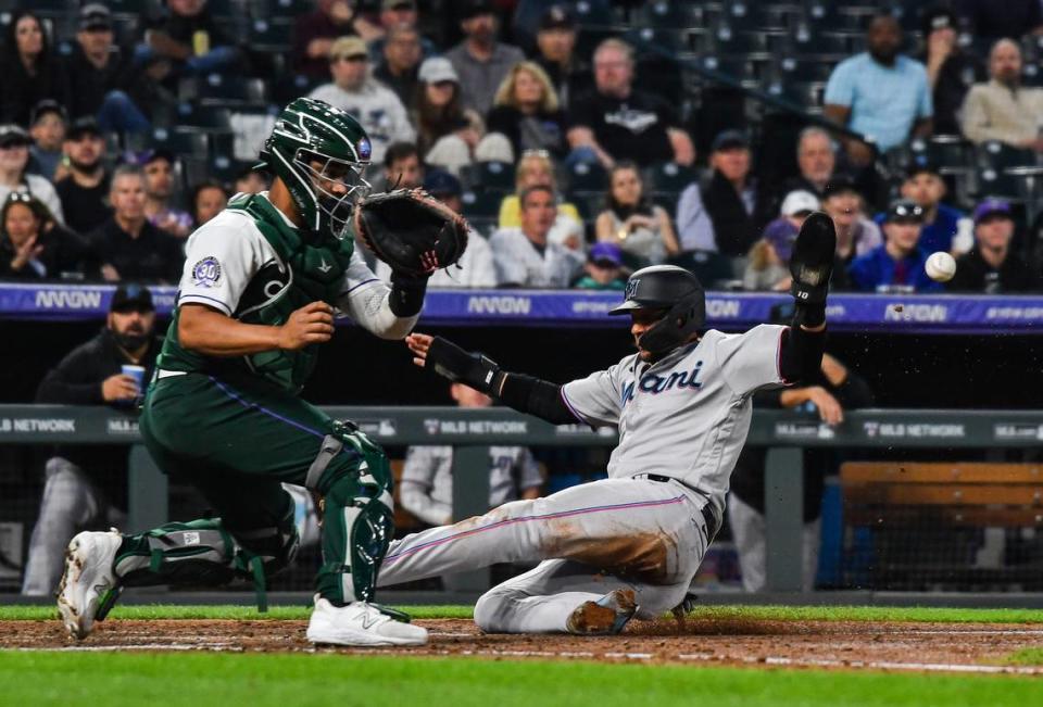 Miami Marlins first baseman Yuli Gurriel (10) slides in at home scoring as Colorado Rockies catcher Elias Diaz (35) receives the throw late in the sixth inning at Coors Field on Wednesday, May 24, 2023.