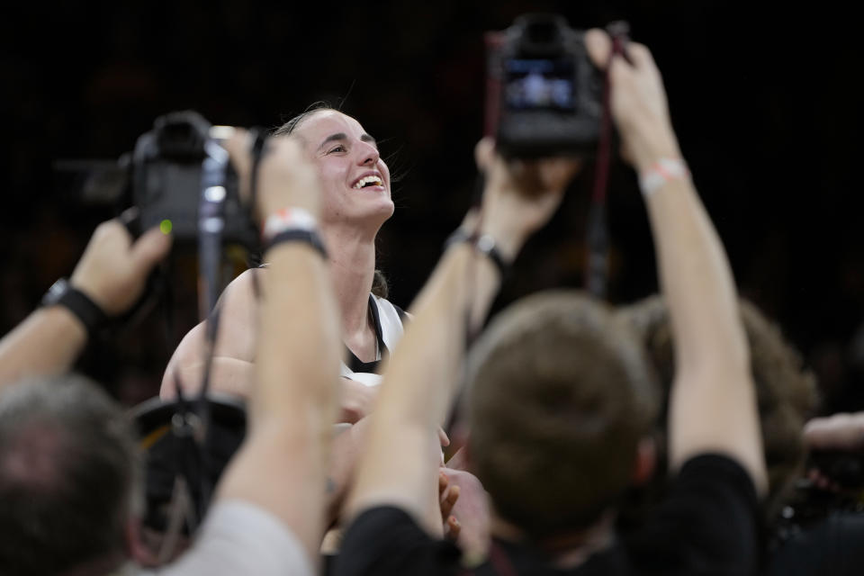 Iowa player hoist Iowa guard Caitlin Clark after she broke the NCAA women's career scoring record in the team's NCAA college basketball game against Michigan, Thursday, Feb. 15, 2024, in Iowa City, Iowa. (AP Photo/Matthew Putney)