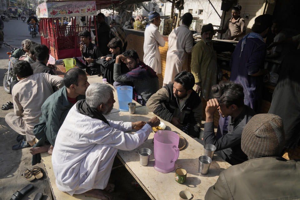 People eat lunch at a roadside restaurant, in Lahore, Pakistan, Tuesday, Feb. 14, 2023. Cash-strapped Pakistan nearly doubled natural gas taxes Tuesday in an effort to comply with a long-stalled financial bailout, raising concerns about the hardship that could be passed on to consumers in the impoverished south Asian country. Pakistan's move came as the country struggles with instability stemming from an economic crisis. (AP Photo/K.M. Chaudary)