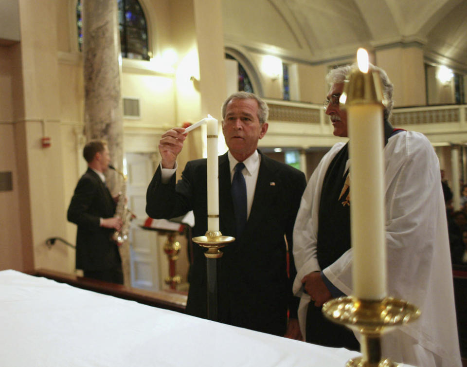 FILE - In this Tuesday, Sept. 11, 2007 photo provided by the White House, President George W. Bush lights a candle accompanied by Rev. Luis Leon, during a service of prayer and remembrance at St. John's Episcopal Church in Washington marking the sixth anniversary of the Sept. 11 terrorist attacks. “If he was in town, he was in church,” Leon said of the younger Bush. (Eric Draper/White House via AP)
