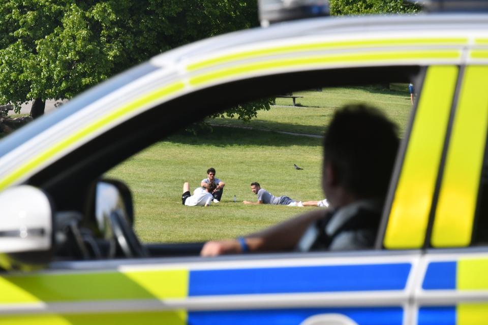 Police officers look at people relaxing in the sunshine on Primrose Hill in London on May 7, 2020 as life continues in Britain under a nationwise lockdown to slow the spread of the novel coronavirus. - British Prime Minister Boris Johnson told senior ministers on May 7 the government would adopt "maximum caution" as it moves towards a relaxation of lockdown measures imposed to combat the coronavirus outbreak. (Photo by JUSTIN TALLIS / AFP) (Photo by JUSTIN TALLIS/AFP via Getty Images)