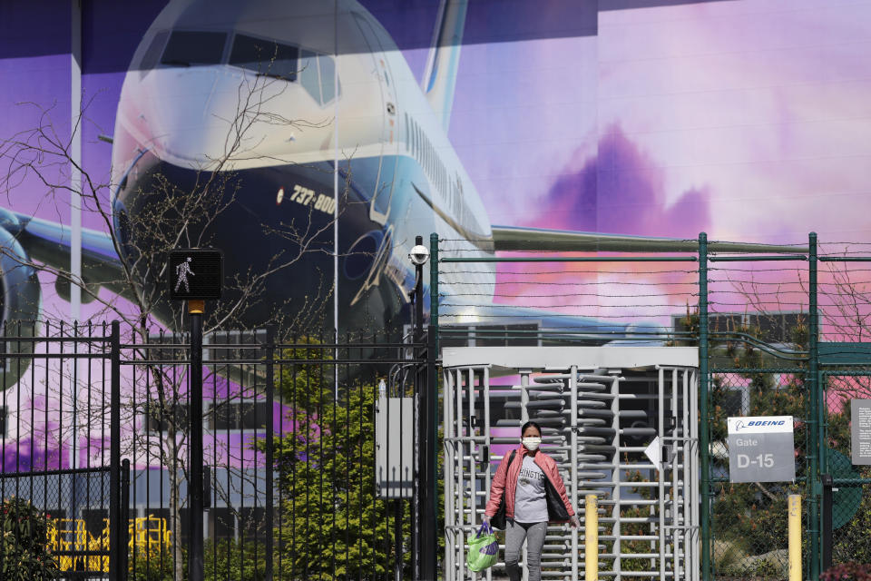 A masked worker departs a gate at a Boeing production plant Monday, April 20, 2020, in Renton, Wash. Boeing this week is restarting production of commercial airplanes in the Seattle area, putting about 27,000 people back to work after operations were halted because of the coronavirus. (AP Photo/Elaine Thompson)