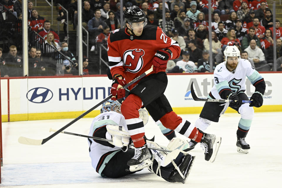 New Jersey Devils center Michael McLeod (20) goes over Seattle Kraken goaltender Philipp Grubauer (31) during the second period of an NHL hockey game Thursday, Feb. 9, 2023, in Newark, N.J. (AP Photo/Bill Kostroun)