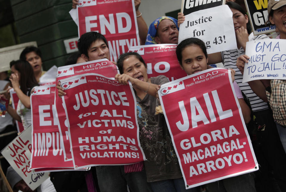 Activists hold slogans against former Philippine President Gloria Macapagal Arroyo as they await her release outside a government hospital in suburban Quezon City, north of Manila, Philippines, Wednesday July 25, 2012. Arroyo on Wednesday was released on bail after a judge found weak evidence linking her to an election sabotage case. (AP Photo/Aaron Favila)