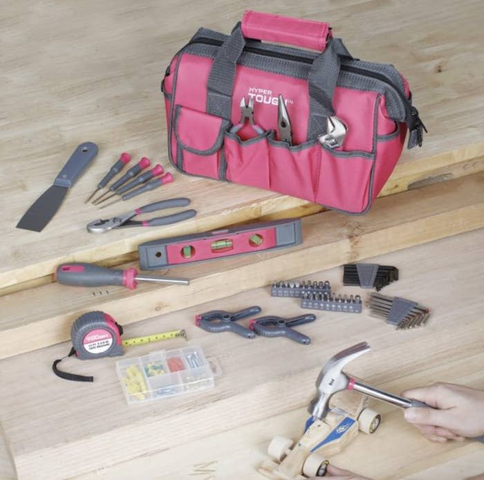 A pink tool kit with a hand hammering a wooden toy car