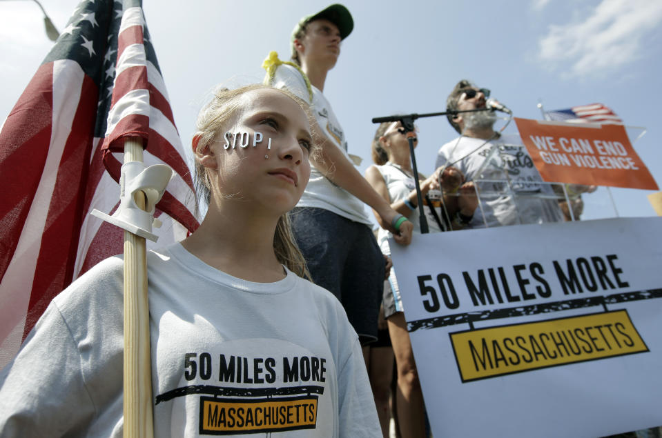 Jessica Sullivan, of Dover, Mass., left, holds an American flag during a rally near the headquarters of gun manufacturer Smith & Wesson, Sunday, Aug. 26, 2018, in Springfield, Mass. The rally was held at the conclusion of a 50-mile march meant to call for gun law reforms that began Thursday, Aug. 23, 2018, in Worcester, Mass., and ended Sunday, in Springfield, near the gun manufacturer. (AP Photo/Steven Senne)