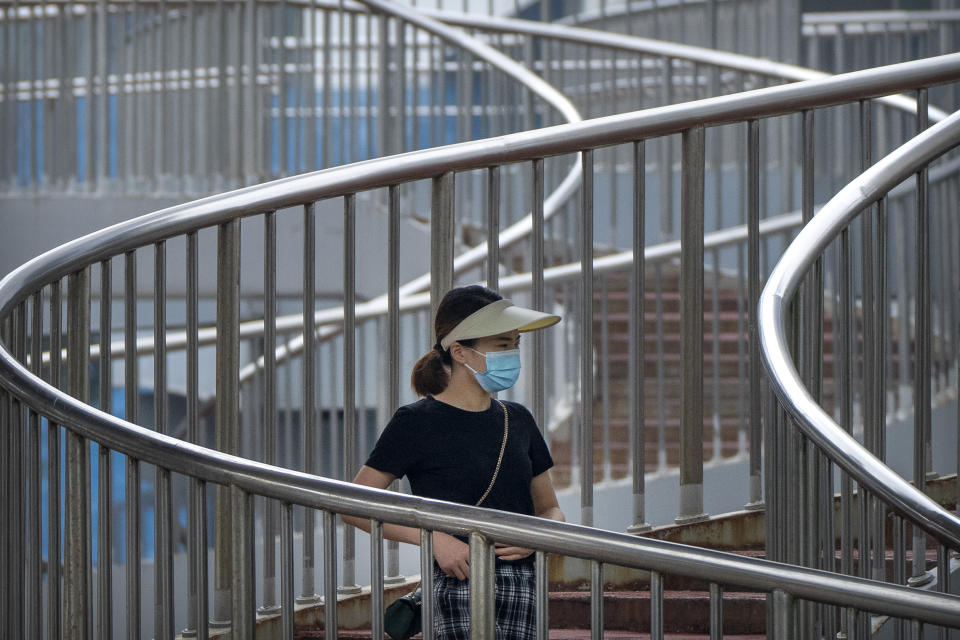 A woman wearing a face mask to protect against COVID-19 walk across a pedestrian bridge during the morning rush hour in Beijing, Wednesday, Aug. 4, 2021. China's worst coronavirus outbreak since the start of the pandemic a year and a half ago escalated Wednesday with dozens more cases around the country, the sealing-off of one city and the punishment of its local leaders. (AP Photo/Mark Schiefelbein)