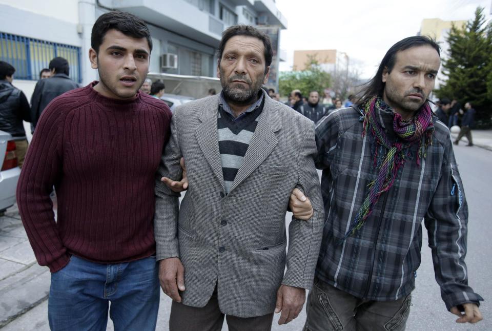 Afghan Fadi Mohamed, survivor of a boat which capsized, , center, who lost his wife and three of his four children, is helped by his son, left, and a fellow countryman who lives in Greece after a prayer at a makeshift basement mosque in western Athens on Friday, Jan. 24, 2014. Twelve people, mostly children, are believed to have perished in Monday's sinking. Only two bodies have been found. Greece's merchant marine minister said Friday the survivors of a fatal migrant boat sinking changed their accounts of the incident, initially saying the Greek Coast Guard saved them but later accusing it of badly mishandling the rescue operation. (AP Photo/Thanassis Stavrakis)