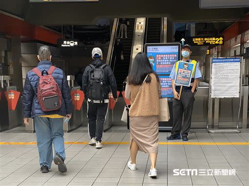 北捷限罩令首日，士林捷運站有警衛舉牌宣導。（圖／讀者提供）