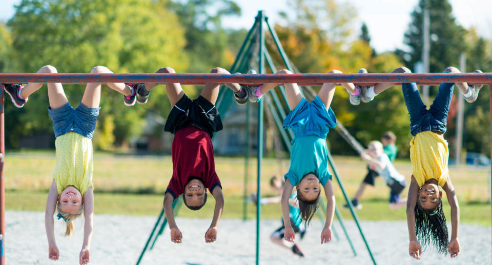 Four children hanging upside down on play equipment