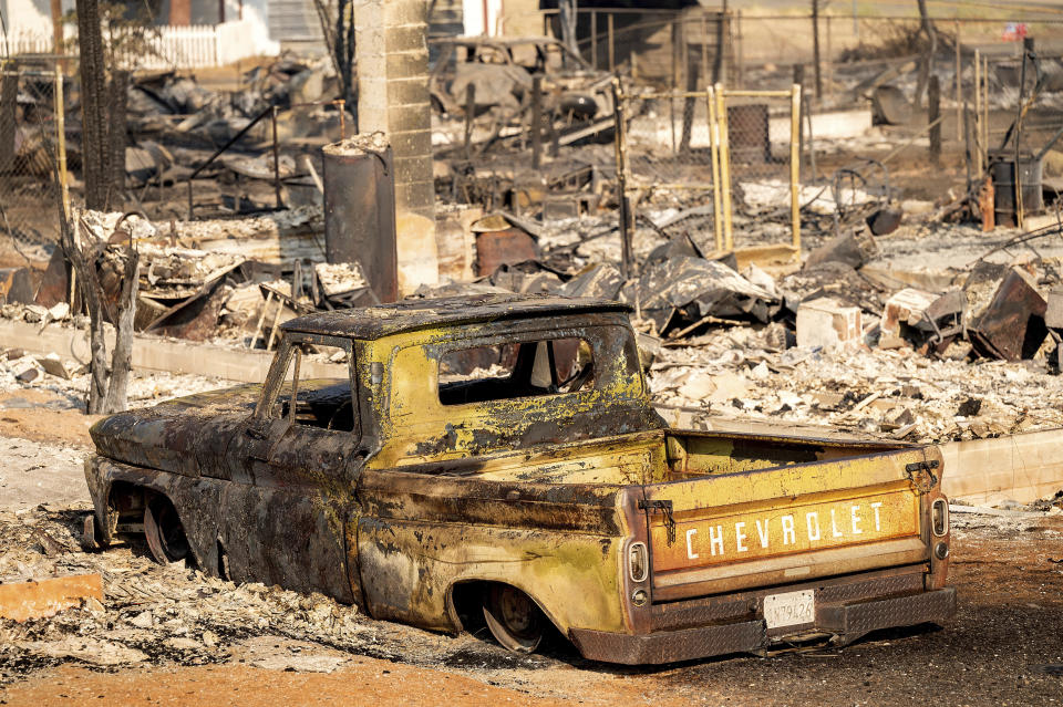A scorched pickup truck sits in front of a Wakefield Avenue home destroyed by the Mill Fire on Saturday, Sept. 3, 2022, in Weed, Calif. (AP Photo/Noah Berger)