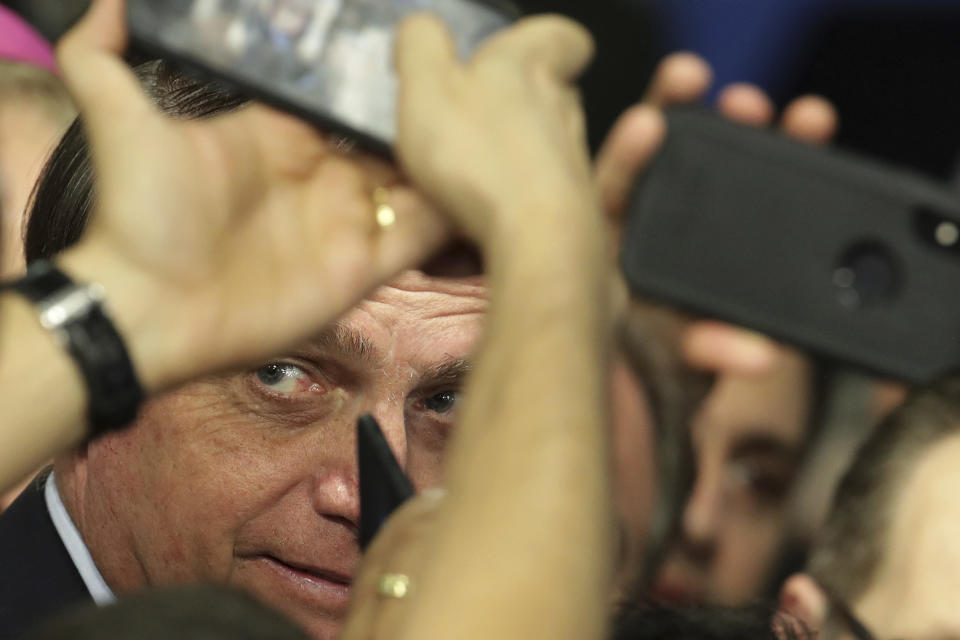 In this Tuesday, May 21, 2019 photo, Brazil's President Jair Bolsonaro poses for photos with supporters after attending a Catholic ceremony at which he dedicated his nation to the Immaculate Heart of Mary at Planalto presidential palace in Brasilia, Brazil. During the ceremony, Bolsonaro was gifted an image of Our Lady of Fatima. (AP Photo/Eraldo Peres)