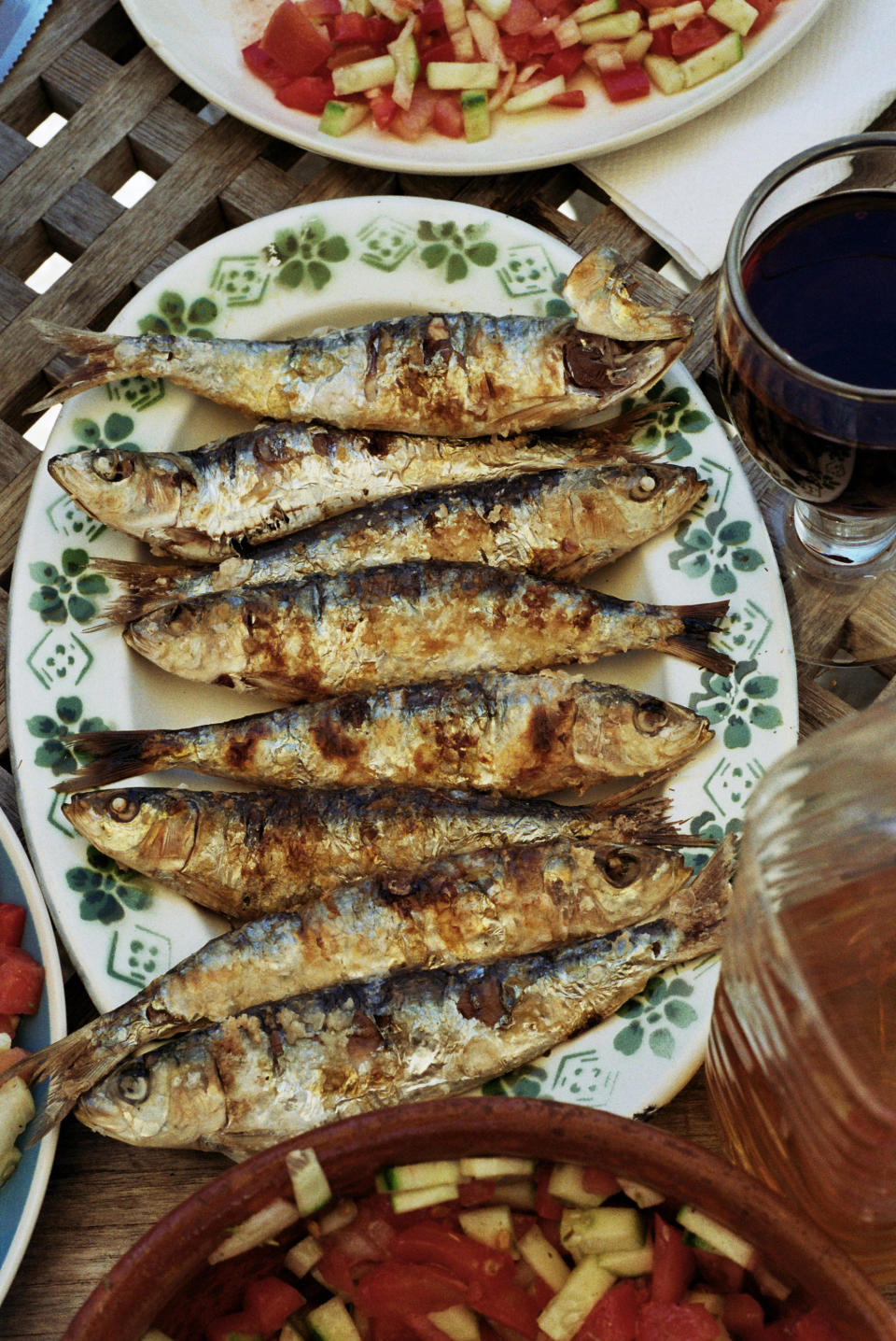 Grilled fish served on a plate with salad on the side and drinks at a meal setting