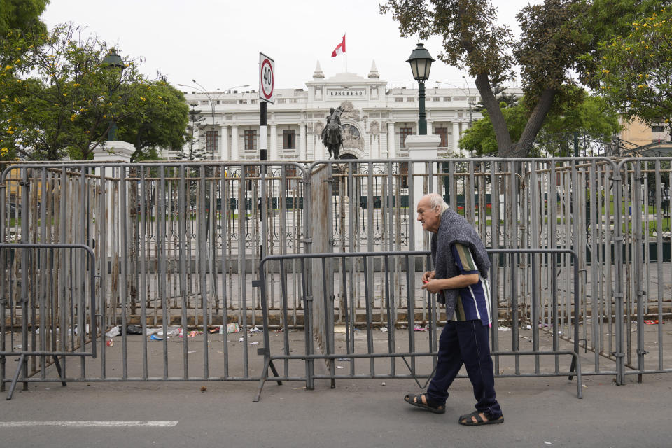 A pedestrian walks past Congress after Peruvian President Pedro Castillo disolved the body on the day lawmakers were planning an impeachment vote on him in Lima, Peru, Wednesday, Dec. 7, 2022. Castillo also called for new legislative elections, before lawmakers could debate a third attempt to remove him from office. (AP Photo/Martin Mejia)