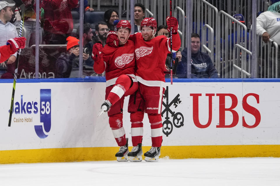 Detroit Red Wings' Lucas Raymond, left, celebrates with teammate J.T. Compher, right, after scoring the winning goal during the overtime period of an NHL hockey game against the New York Islanders, Monday, Oct. 30, 2023, in Elmont, N.Y. (AP Photo/Frank Franklin II)