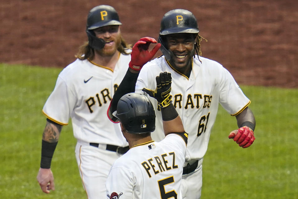 Pittsburgh Pirates' Oneil Cruz (61) celebrates with Ben Gamel, rear, and Michael Perez (5) as he returns to the dugout after hitting a two-run home run, his first in the Major League, off Cincinnati Reds relief pitcher Mychal Givens during the ninth inning of a baseball game in Pittsburgh, Sunday, Oct. 3, 2021. The Reds won 6-3. (AP Photo/Gene J. Puskar)