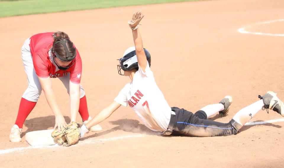 Milan's Cami Heath dives back into third base during a 15-0 win over Grosse Ile on Monday, May 13, 2024.