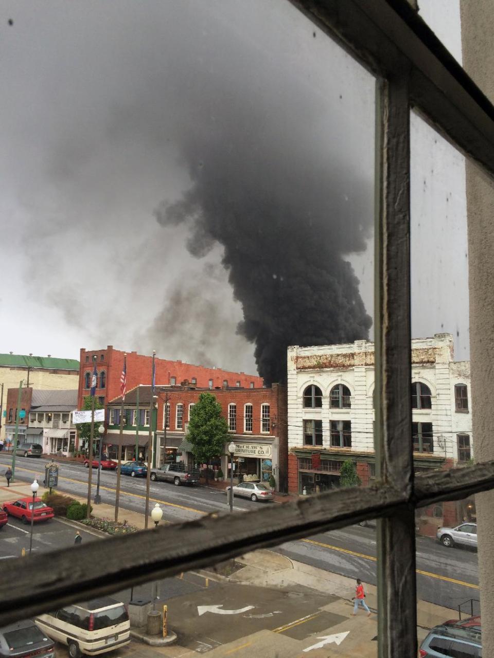 In this mobile phone photo provided Charles Peters, smoke rises after several CSX tanker cars carrying crude oil derailed on Wednesday, April 30, 2014, in Lynchburg, Va. Authorities evacuated numerous buildings Wednesday after the derailment. (AP Photo/Charles Peters) MANDATORY CREDIT