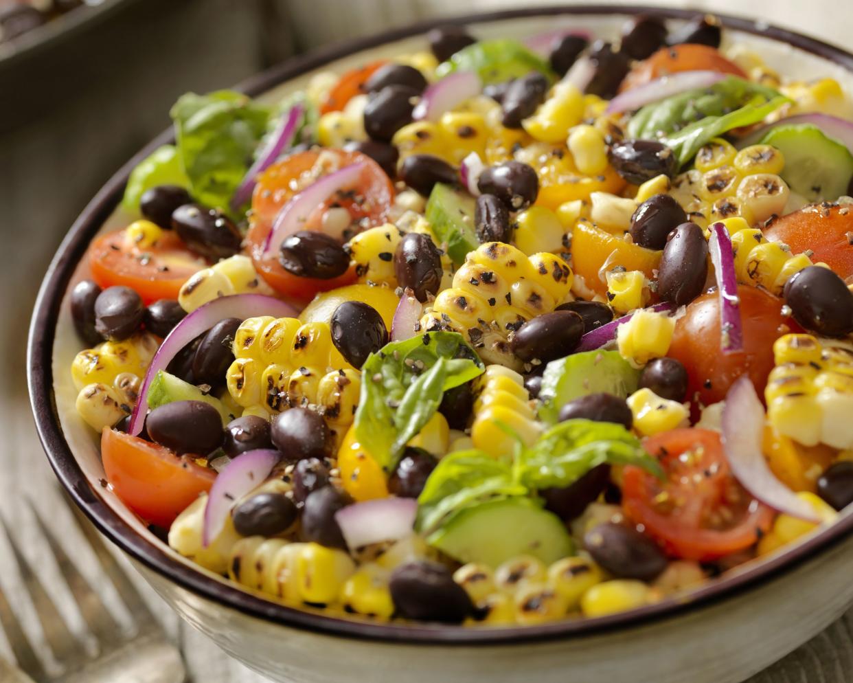 Black Bean and Corn Salad with cherry tomatoes, red onions and basil leaves