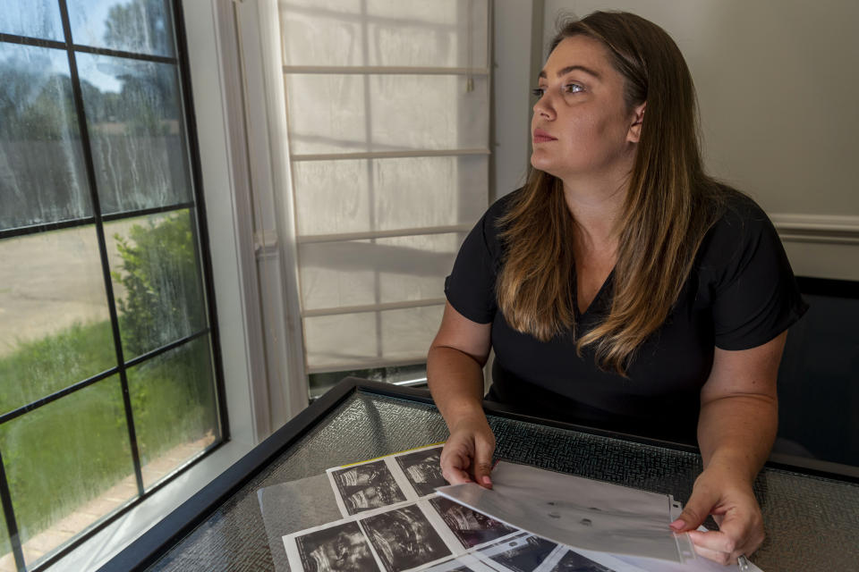 In this Aug. 29, 2019, photo, Hevan Lunsford poses for a photo with her son's ultrasounds and footprints and handprints of her son, in Prattville, Ala. Lunsford found out when she was five months pregnant that the baby she would later name Sebastian was severely underdeveloped and had only half of a heart. Lunsford said she felt the only way to guarantee her son would not suffer would be to end the pregnancy and was told she would need to travel to Georgia for the procedure. Lunsford is one of thousands of women across the U.S. in recent years who have crossed state lines for an abortion. (AP Photo/Vasha Hunt)