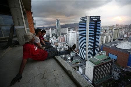 Men rest after salvaging metal on the 30th floor of the "Tower of David" skyscraper in Caracas February 3, 2014. It boasts a helicopter landing pad, glorious views of the Avila mountain range, and large balconies for weekend barbecues. Yet a 45-storey skyscraper in the center of Venezuela's capital Caracas is no five-star hotel or swanky apartment block: it is a slum, probably the highest in the world. Dubbed the "Tower of David", the building was intended to be a shining new financial center but was abandoned around 1994 after the death of its developer - banker and horse-breeder David Brillembourg - and the collapse of the financial sector. REUTERS/Jorge Silva