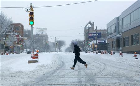 A man runs across the street, as a winter storm moves across the midwest, in Milwaukee, Wisconsin December, 22, 2013. REUTERS/Darren Hauck