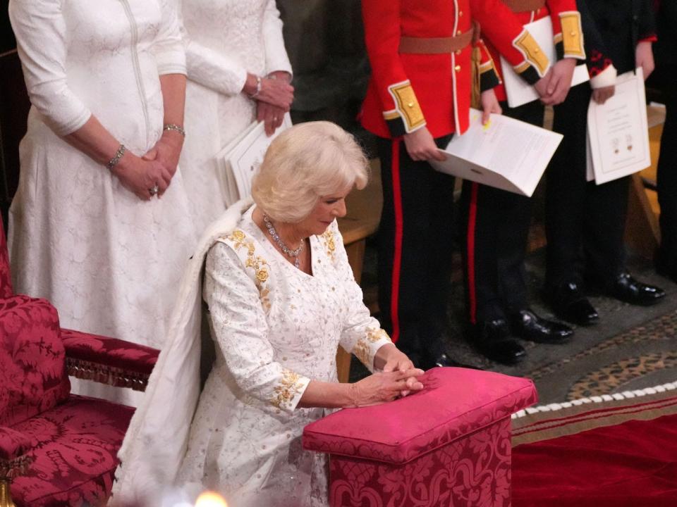 Queen Camilla kneels during the coronation ceremony.