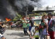 Residents evacuate into the streets as houses burn in a residential district after a clash between government soldiers and Muslim rebels from the Moro National Liberation Front (MNLF) in Zamboanga city in southern Philippines September 12, 2013. (REUTERS/Erik De Castro)