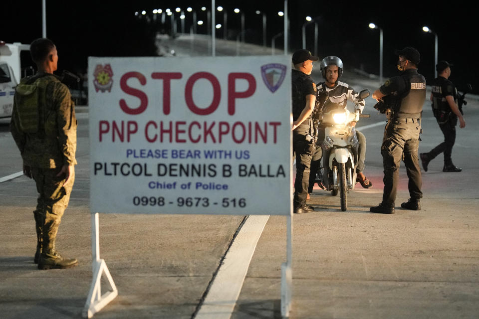 Police stop a motorcycle rider at a checkpoint at the border of the "permanent danger zone" around Mayon volcano at Daraga town, Albay province, northeastern Philippines, Tuesday, June 13, 2023. Truckloads of villagers on Tuesday fled from Philippine communities close to gently erupting Mayon volcano, traumatized by the sight of red-hot lava flowing down its crater and sporadic blasts of ash. (AP Photo/Aaron Favila)