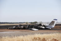 The burned out remains of a twin-engine Cessna Citation sits at the end of a runway after the pilot aborted the takeoff at the Oroville Airport in Oroville, Calif., Wednesday, Aug. 21, 2019. The plane carried two pilots and eight passengers, who all escaped injury. Firefighters were able to quickly control a grass fire that broke out and temporarily closed Highway 162. No cause of the crash has been listed. (AP Photo/Rich Pedroncelli)