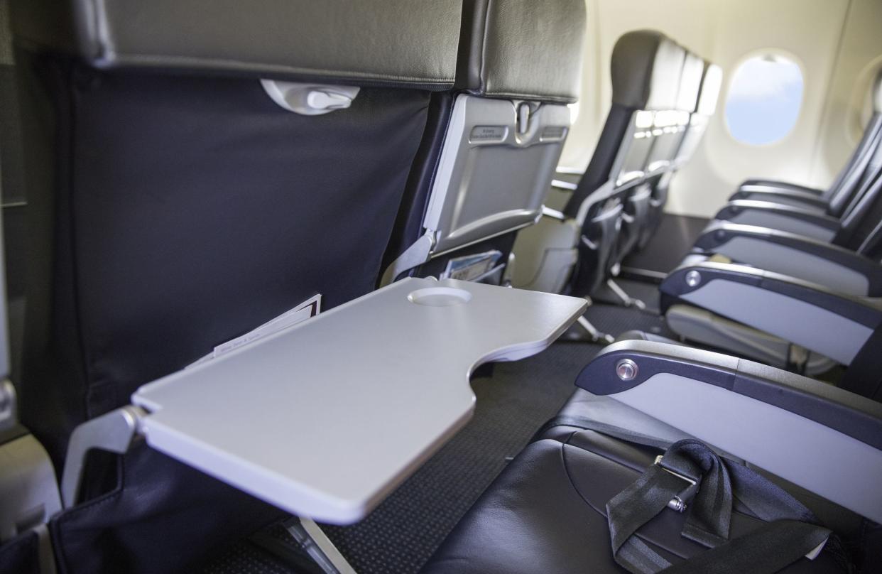 Inside of empty airplane. There is a row of seats and the seat closest has the tray table in the down position. Shot with Canon 5D Mark lV.