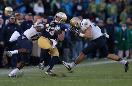 SOUTH BEND, IN - NOVEMBER 02: Cam McDaniel #33 of the Notre Dame Fighting Irish is hit by Kwazel Bertrand #17 and D.J. Sargenti #52 of the Navy Midshipmen at Notre Dame Stadium on November 2, 2013 in South Bend, Indiana. Notre Dame defeated Navy 38-34. (Photo by Jonathan Daniel/Getty Images)