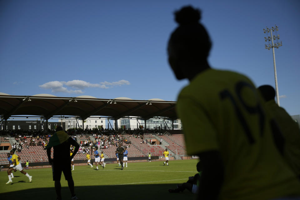 Substitutes watch the players during the women's final game of the national cup of working-class neighborhoods betwwen a team representing players with Malian heritage in yellow against one with Congolese roots, in Creteil, outside Paris, France, Saturday, July 2, 2022. This amateur tournament aims to celebrate the diversity of youth from low-income communities with high immigrant populations, areas long stigmatized by some observers and politicians as a breeding ground for crime, riots, and Islamic extremism. (AP Photo/ Christophe Ena)