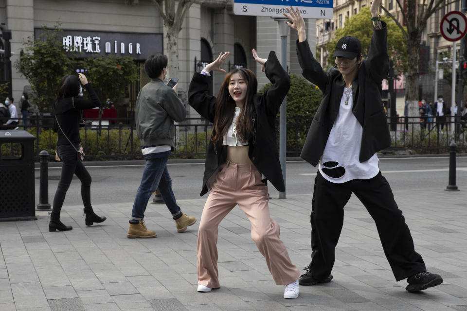 Youths remove their mask to record a dance routine on the streets of Wuhan in central China's Hubei province, April 8, 2020. Released from their apartments after a 2 1/2-month quarantine, residents of the city where the coronavirus pandemic began are cautiously returning to shopping and strolling in the street but say they still go out little and keep children home while they wait for schools to reopen. (AP Photo/Ng Han Guan)