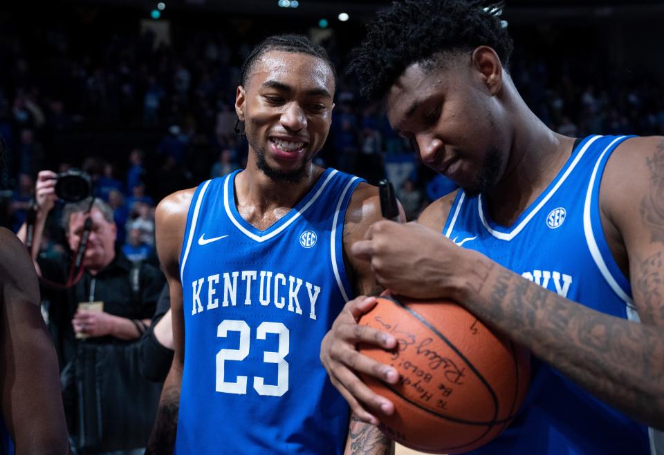 Wildcats guards Jordan Burks (23) and Justin Edwards sign a basketball for a fan after UK's victory against host Vanderbilt on Tuesday night.
