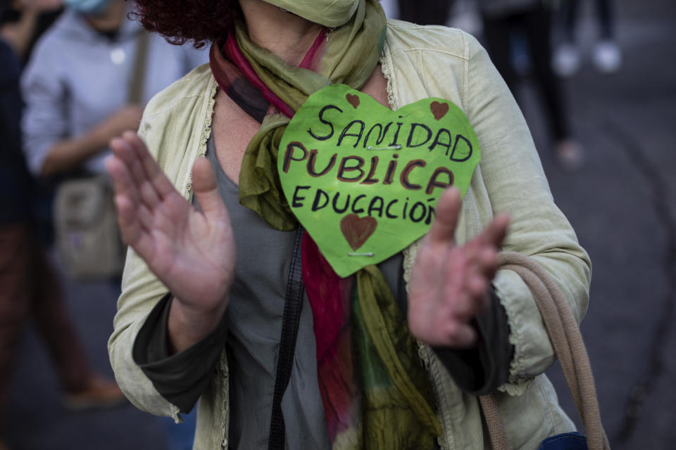 Residents of restricted mobility areas in Madrid due to the coronavirus outbreak gather during a protest to demand more resources for public health system and against social inequality in the southern neighbourhood of Vallecas, Madrid, Spain, Thursday, Sept. 24, 2020. The regional government is set to announce Friday new restrictions in Madrid, where gatherings are limited to a maximum of 6 people and more than 850,000 residents have been partially locked down this week. The text reads in Spanish "public health & education". (AP Photo/Bernat Armangue)