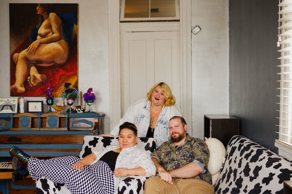 three people sit together on a cow-printed couch in their home in new orleans