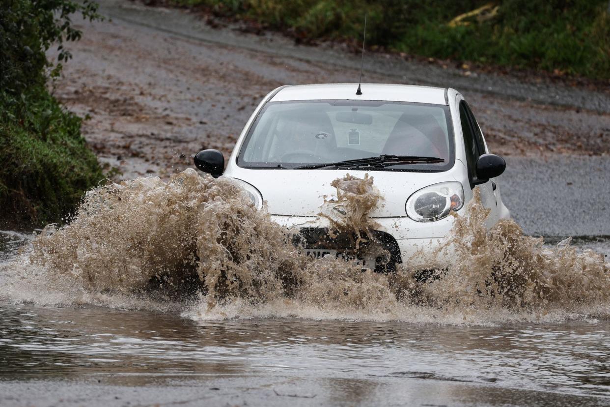 A car drives along a flooded road in Romsey, southern England (AFP via Getty Images)
