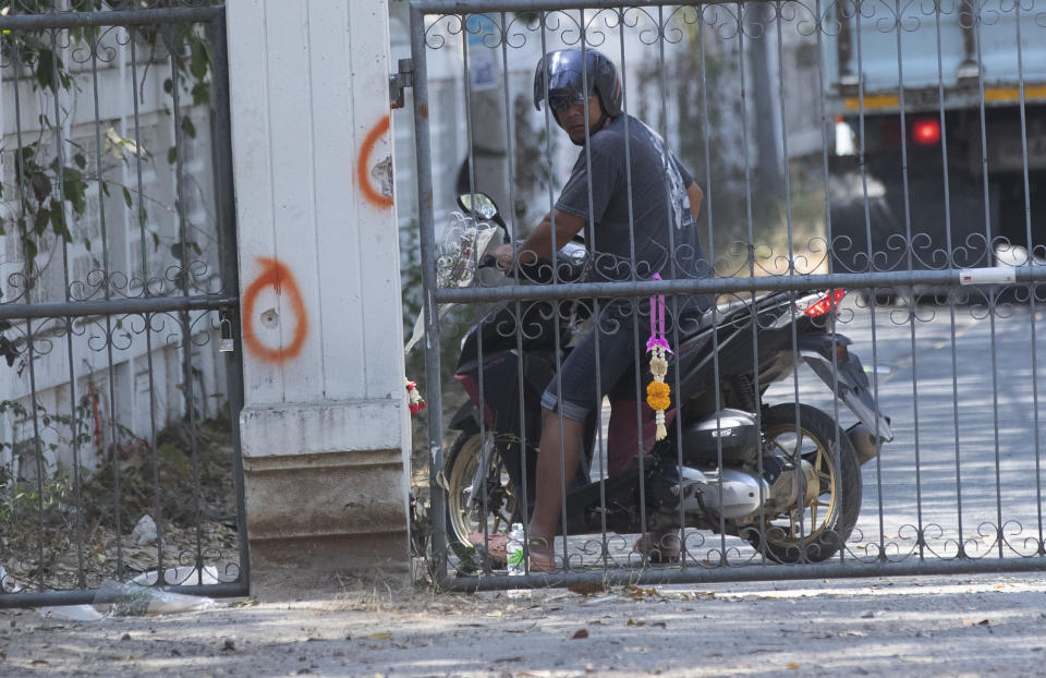 A motorcyclist stops to view one of the scenes of a mass shooting at the weekend's mass shooting that partially took place at the Wat Pa Sattharuam temple, Tuesday, Feb. 11, 2020, in Korat, Nakhon Ratchasima, Thailand. A rogue Thai soldier whose rampage left 29 people dead and dozens more injured terrorized a Buddhist temple complex in rural northeastern Nakhon Ratchasima province on his way to a shopping mall, where he held shoppers hostage in a nearly 16-hour siege. (AP Photo/Sakchai Lalit)