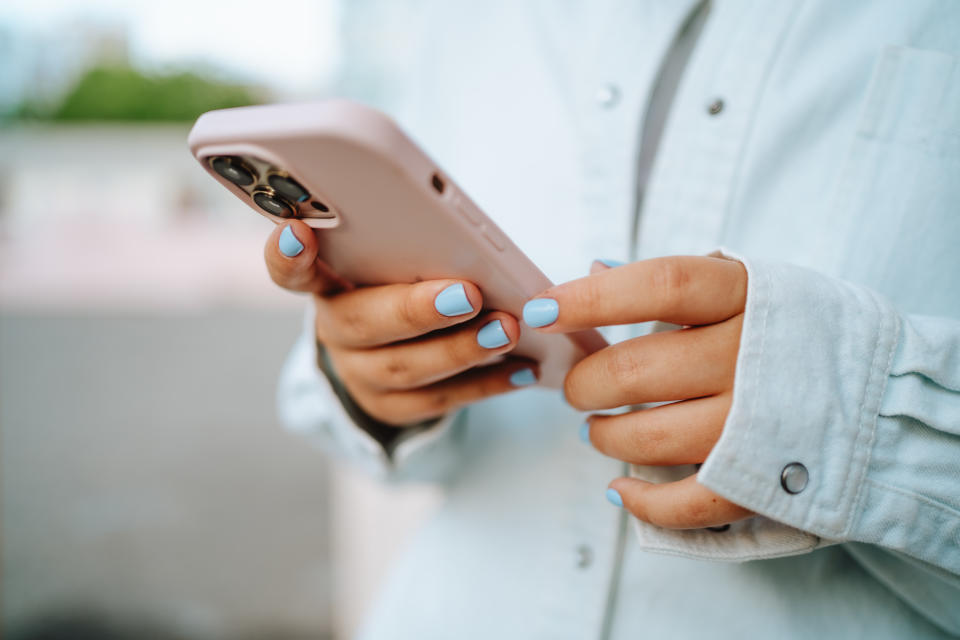 A person holding their phone and using social media. (Photo via Getty Images)