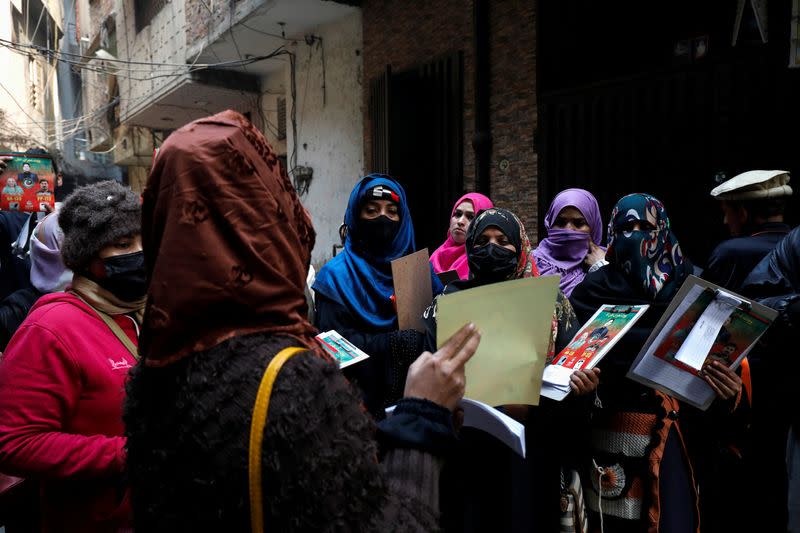 Komal Asghar speaks with fellow teachers before they start a door-to-door campaign, ahead of the general elections in Lahore