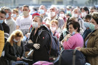 Romanian seasonal workers wait outside the Avram Iancu international airport, in Cluj, central Romania, Thursday, April 9, 2020. More then 1800 workers from across Romania are traveling on 12 flights to Berlin, Baden Bade and Dusseldorf in Germany, most of them to work in asparagus farms.(AP Photo/Raul Stef)