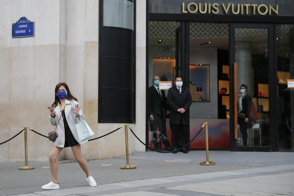 A woman gestures in front of a luxury shop that opens Monday, May 11, 2020 in Paris. he French began leaving their homes and apartments for the first time in two months without permission slips as the country cautiously lifted its lockdown. Clothing stores, coiffures and other businesses large and small were reopening on Monday _ with strict precautions to keep the coronavirus at bay. (AP Photo/Francois Mori)