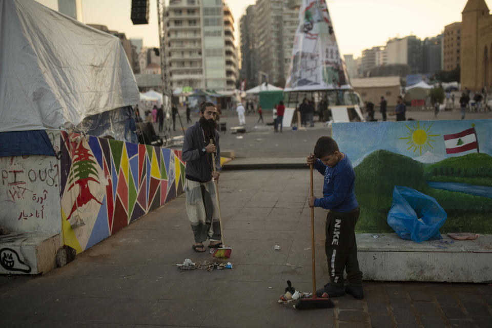 FILE - In this Dec. 21, 2019, file, photo, volunteers sweep trash in the central square where anti-government protesters have set up camp in downtown Beirut, Lebanon. Lebanon is entering its third month of protests, the economic pinch is hurting everyone, and the government is paralyzed. So people are resorting to what they've done in previous crises: They rely on each other, not the state. (AP Photo/Maya Alleruzzo, File)