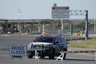 A Texas Department of Public Safety vehicle stands at a road block near the Del Rio International Bridge, which remains closed due to a migrant encampment alongside the bridge, Friday, Sept. 24, 2021, in Del Rio, Texas. The “amistad,” or friendship, that Del Rio, Texas, and Ciudad Acuña, Mexico, celebrate with a festival each year has been important in helping them deal with the challenges from a migrant camp that shut down the border bridge between the two communities for more than a week. Federal officials announced the border crossing would reopen to passenger traffic late Saturday afternoon and to cargo traffic on Monday. (AP Photo/Julio Cortez)